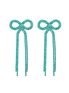 Close-up of sparkling bowknot earrings with turquoise rhinestones and long tassels