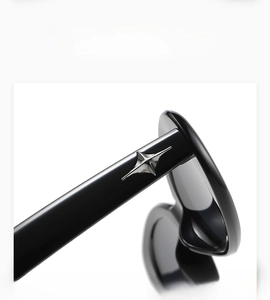 Macro detail of glossy black sunglasses frame with silver metal star embellishment on temple