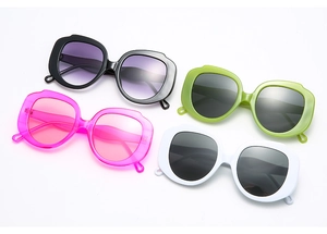 Flat lay of oversized round sunglasses in black, pink, green and white glossy frames