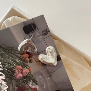 Detailed view of silver heart earrings with lava texture in a premium gift box