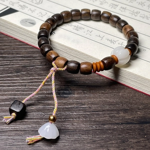 Close-up of wooden bead bracelet with white Bodhi seed pendant on a calligraphy book