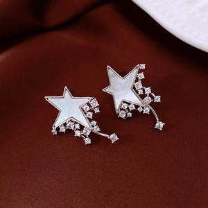 Macro shot of silver star stud earrings featuring mother of pearl and zircon tassels