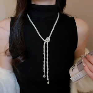Long pearl necklace with crystal teardrop pendant shown on a black turtleneck model