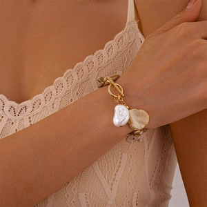 Close-up of golden toggle clasp bracelet with baroque pearl and shell charms