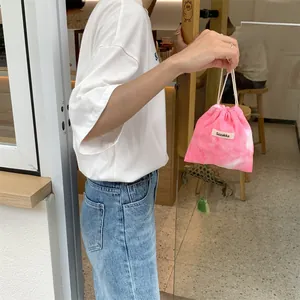 Pink and white tie-dye corduroy drawstring bag with Sozakka brand label being held by hand