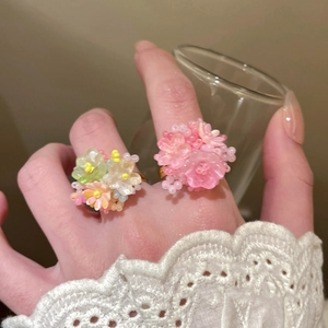 Detail of colorful resin beaded flower rings with pink and macaron petals on gold band