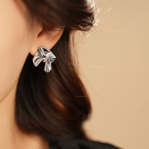 Close-up of sculptural silver earrings featuring a sleek, minimalist metallic design