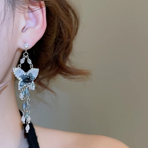 Gros plan de boucles d'oreilles papillon en cristal à pompons portées par un mannequin