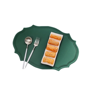 Dark green faux leather placemat with irregular scalloped edges and a plate of pastries