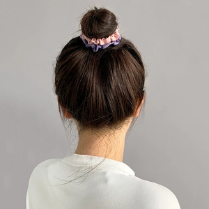 Detail of pink and gray purple satin scrunchie on a bun hairstyle for women