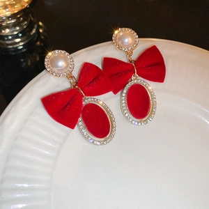 Détail des boucles d'oreilles nœud en velours rouge avec perles et cristaux sur une assiette