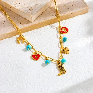 Golden link necklace with red heart lock, cowboy boot, and leaf pendants on stone base