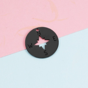 Macro shot of a 22mm black stainless steel compass pendant with star cutout detail