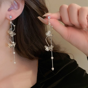 Detail of silver long tassel earrings with hollow butterfly design and white pearls