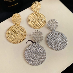 Detailed macro view of hollow woven round pendant earrings in gold and silver finish