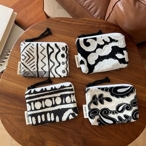 Bohemian black and white linen mini coin purses with tassels on a wooden table