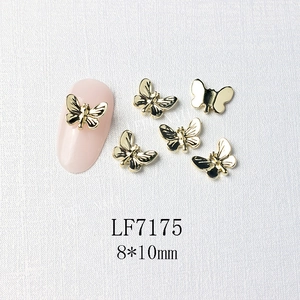 Macro view of 8x10mm golden butterfly nail charm with black detailing and pink nail model