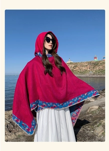Close-up of red hooded poncho with ethnic embroidery and white trim at lakeshore