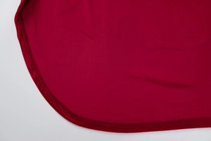 Gros plan détaillé de la robe en maille rouge montrant l'ourlet arrondi et la couture