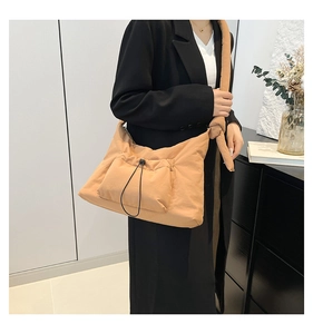 Detail of apricot padded tote bag featuring a front drawstring pocket and wide knotted strap