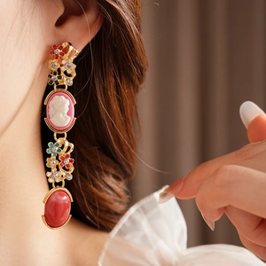 Detailed shot of a vintage gold drop earring with enamel flowers and a cameo portrait