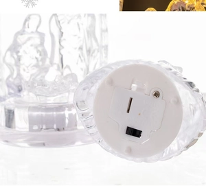Detailed bottom view of clear LED holy family ornament showing battery compartment and switch