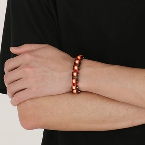 Close-up of industrial style red and black steel bike chain bracelet on a wrist