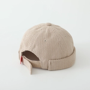 Detail of adjustable velcro strap and red label on beige corduroy docker hat for boys