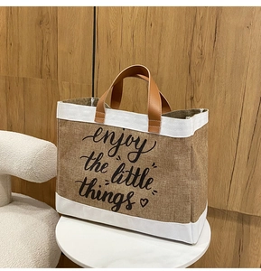 Dettaglio borsa in lino con manici in pelle e scritta stampata enjoy the little things