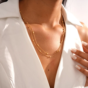 Close-up of double-layer golden necklace with rice-shaped metal beads on model