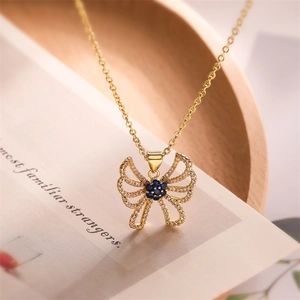 Close-up of gold butterfly pendant with dark blue gemstone and sparkling crystals