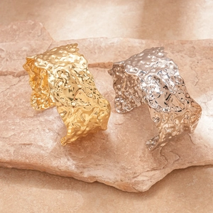 Modern gold and silver hammered metal open cuff bracelets on a natural stone base
