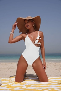 Detail of white cutout swimsuit with sequined starfish on a sunny beach setting