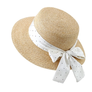 Chapeau de paille français avec ruban à pois blancs et nœud sur fond blanc pur