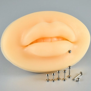 Detail view of G23 titanium labret studs in various lengths with a silicone lip model
