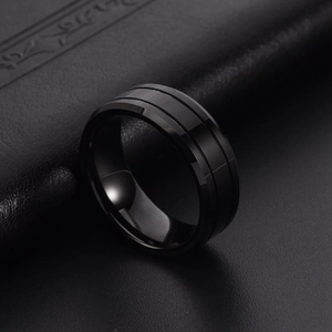 Polished black tungsten ring for men featuring striped accents on a dark leather surface