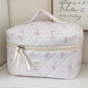 Detail of white quilted makeup bag with pink bows, gray dots and beige ribbon puller