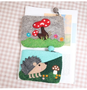 Detail of wool felt coin purses with cute mushroom and hedgehog patterns and zippers
