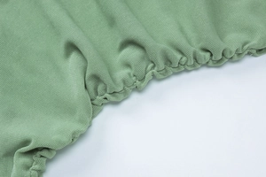 Detail of green knitted fabric with elastic ruching and fine mesh texture on a summer set