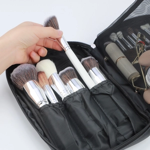 Detail of portable black makeup brush bag with elastic slots and multiple brushes