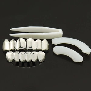 Silver hip hop teeth grillz set with molding bars and tweezers on a black surface