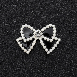 Detail of a black enamel bow charm with pearl border and a large central crystal
