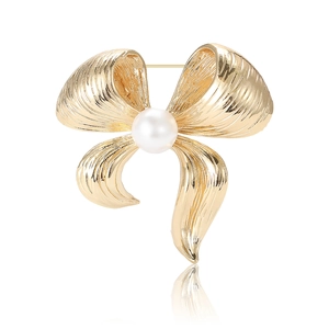 Elegant gold bow brooch with a large pearl center on a white background with reflection