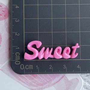 Breloque Sweet en résine rose sur tapis de découpe pour bricolage de barrettes