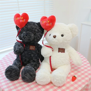 Close-up of black and white teddy bears with red hearts and love-themed English text