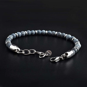 Detail of beaded map stone bracelet with stainless steel lobster clasp and logo tag