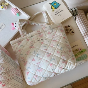 Detailed close-up of a quilted floral tote bag with cute rabbit prints and a textile label