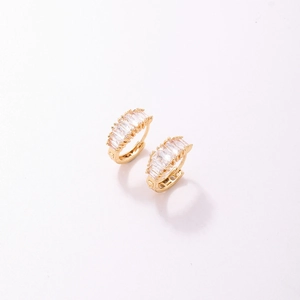 Détail de boucles d'oreilles huggie dorées avec oxydes de zirconium baguettes et griffes