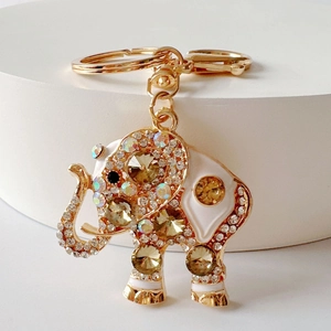 Close-up of golden elephant keychain with white enamel and sparkling rhinestones