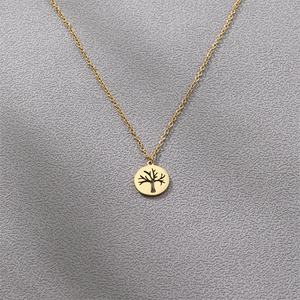 Golden stainless steel tree of life pendant necklace displayed on a textured grey background
